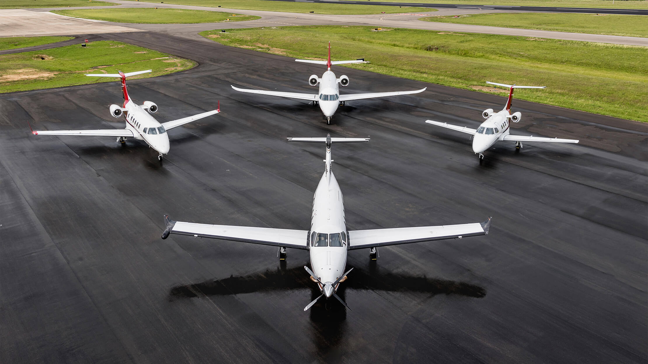 Four Jets on a Runway including a Pilatus PC-12, Embraer Phenom 100, Embraer Phenom 300, and a Citation Latitude